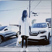 a man in a white shirt standing next to a car