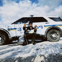 a man is posing in front of a police car